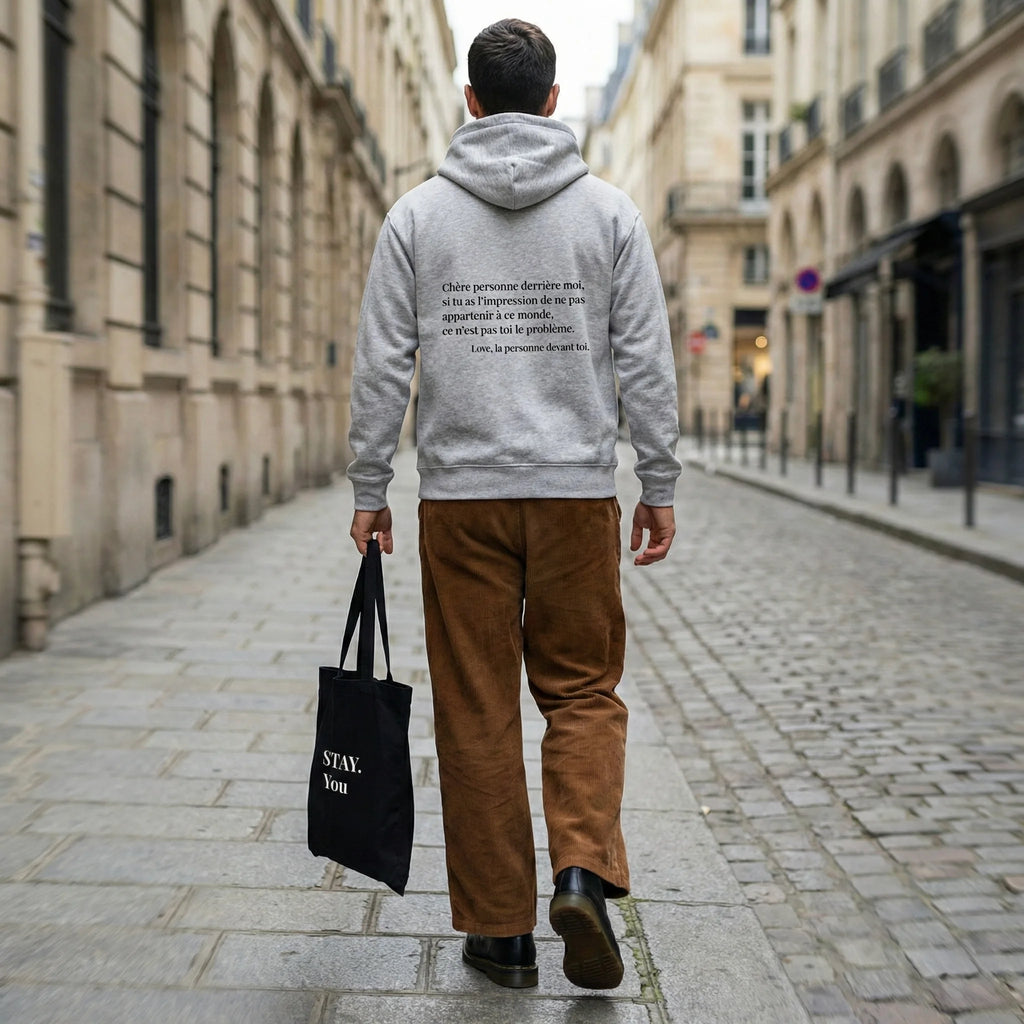 homme marche dans la rue, portant hoodie gris message au dos 
